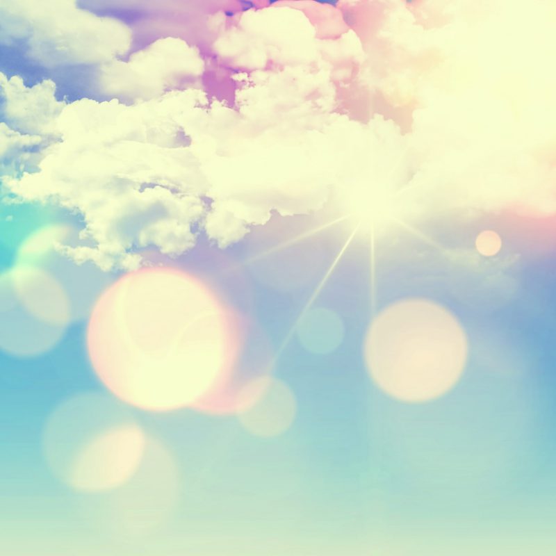 Sunny blue sky background with fluffy white clouds and retro effect added